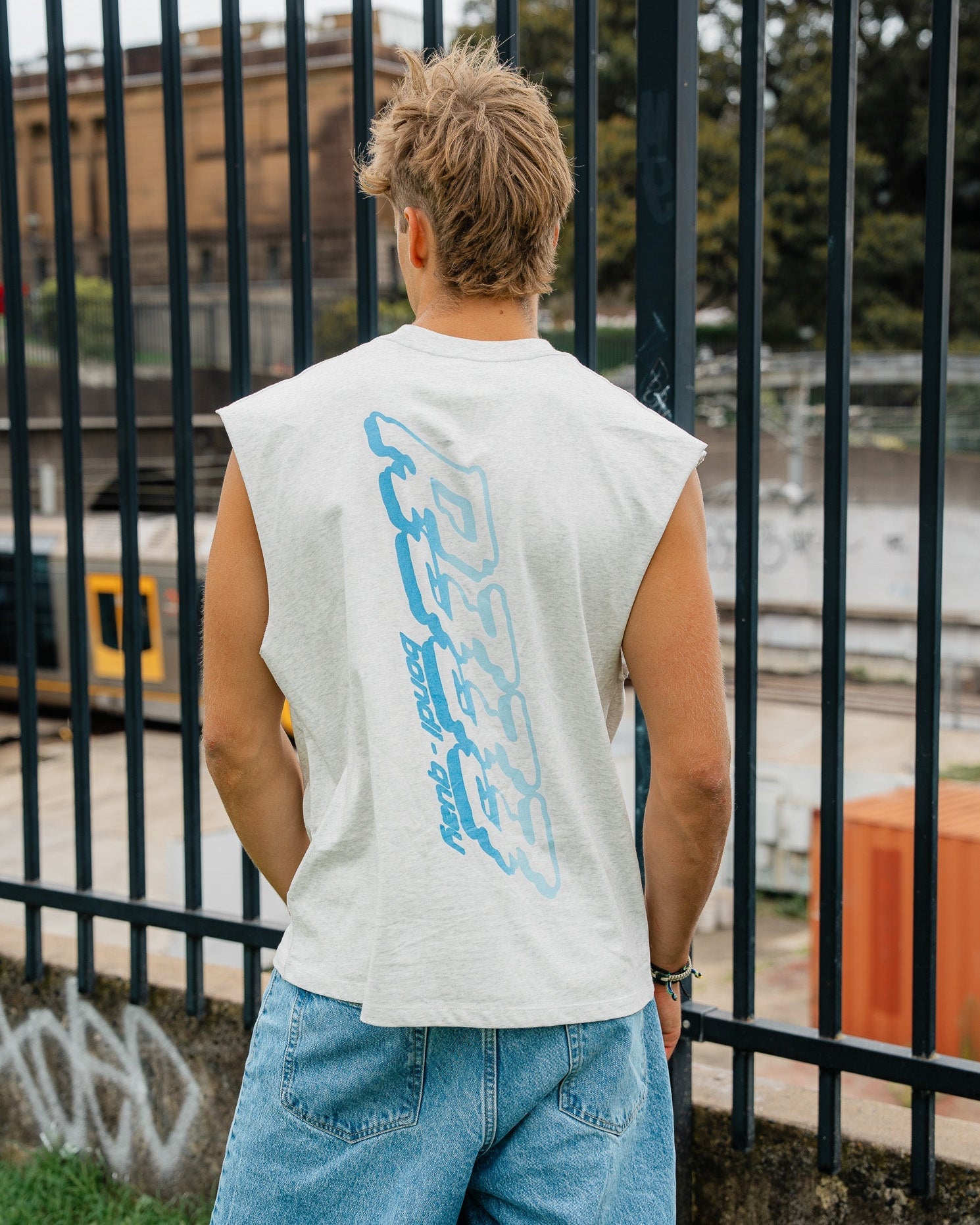 Guy standing near a fence wearing a route 333 tank top that has a blue graphic