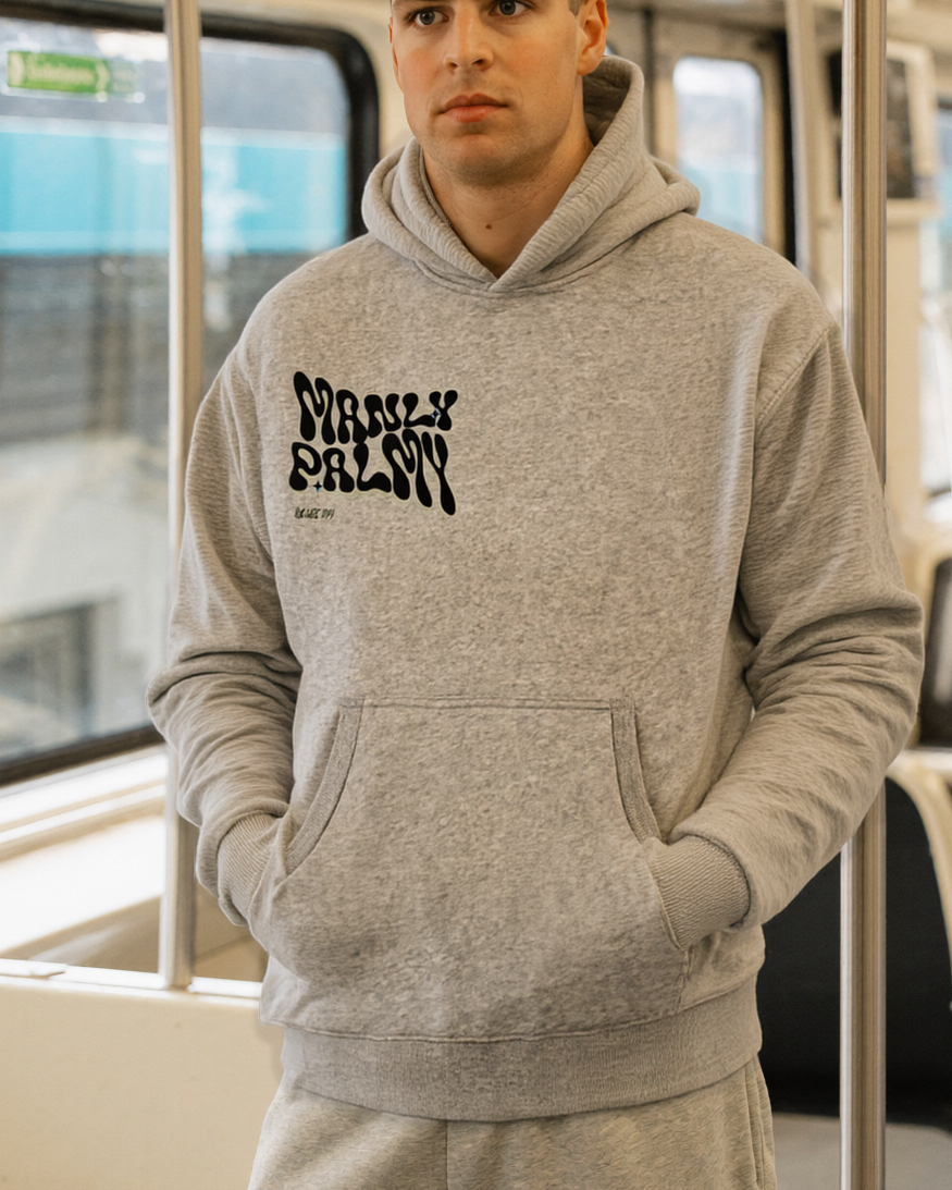 Person wearing a gray hoodie with text on it, standing inside a train.