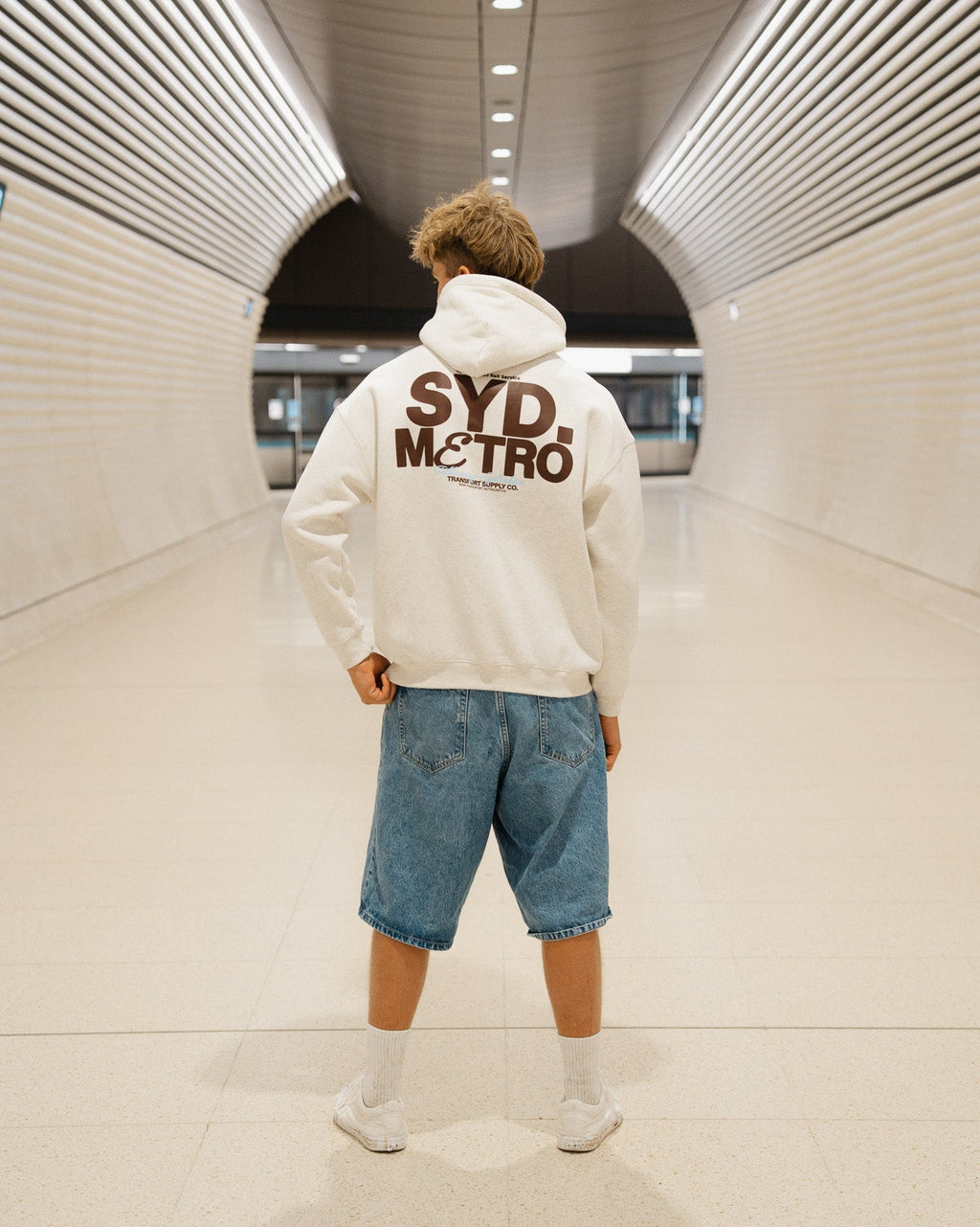 Person wearing a white hoodie with 'SYD METRO' text in a tunnel.