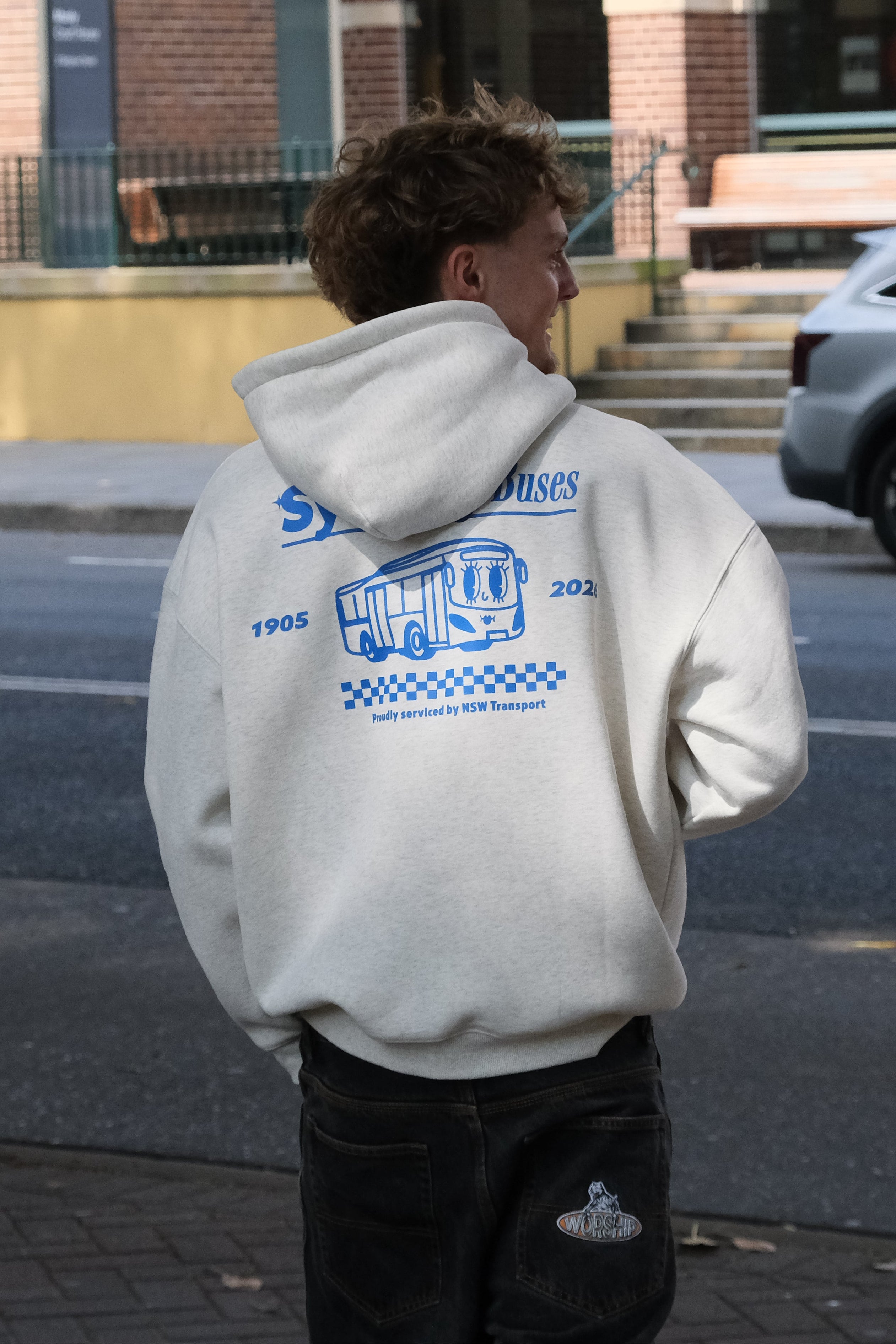 Person wearing a hoodie with visible branding on a city street.