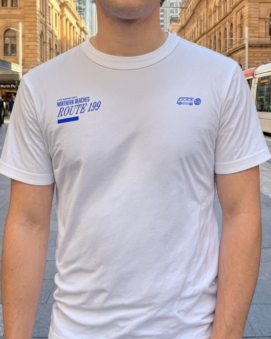 Person wearing a white 199 bus t-shirt with text and logos in an urban setting